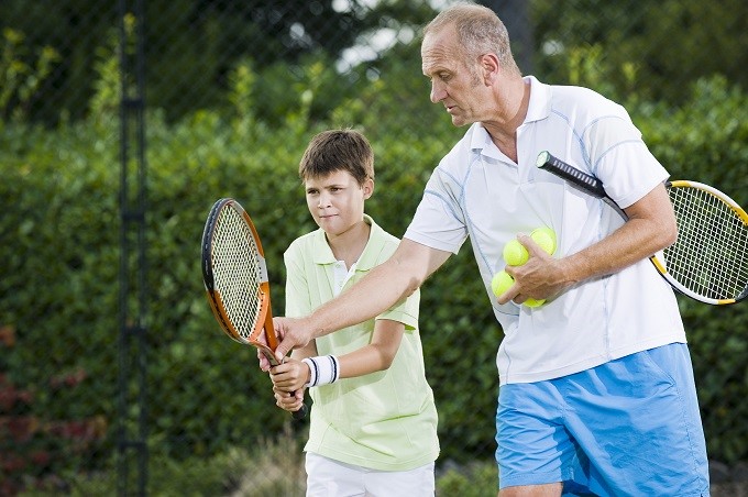 Young boy having tennis lessons from an instructor