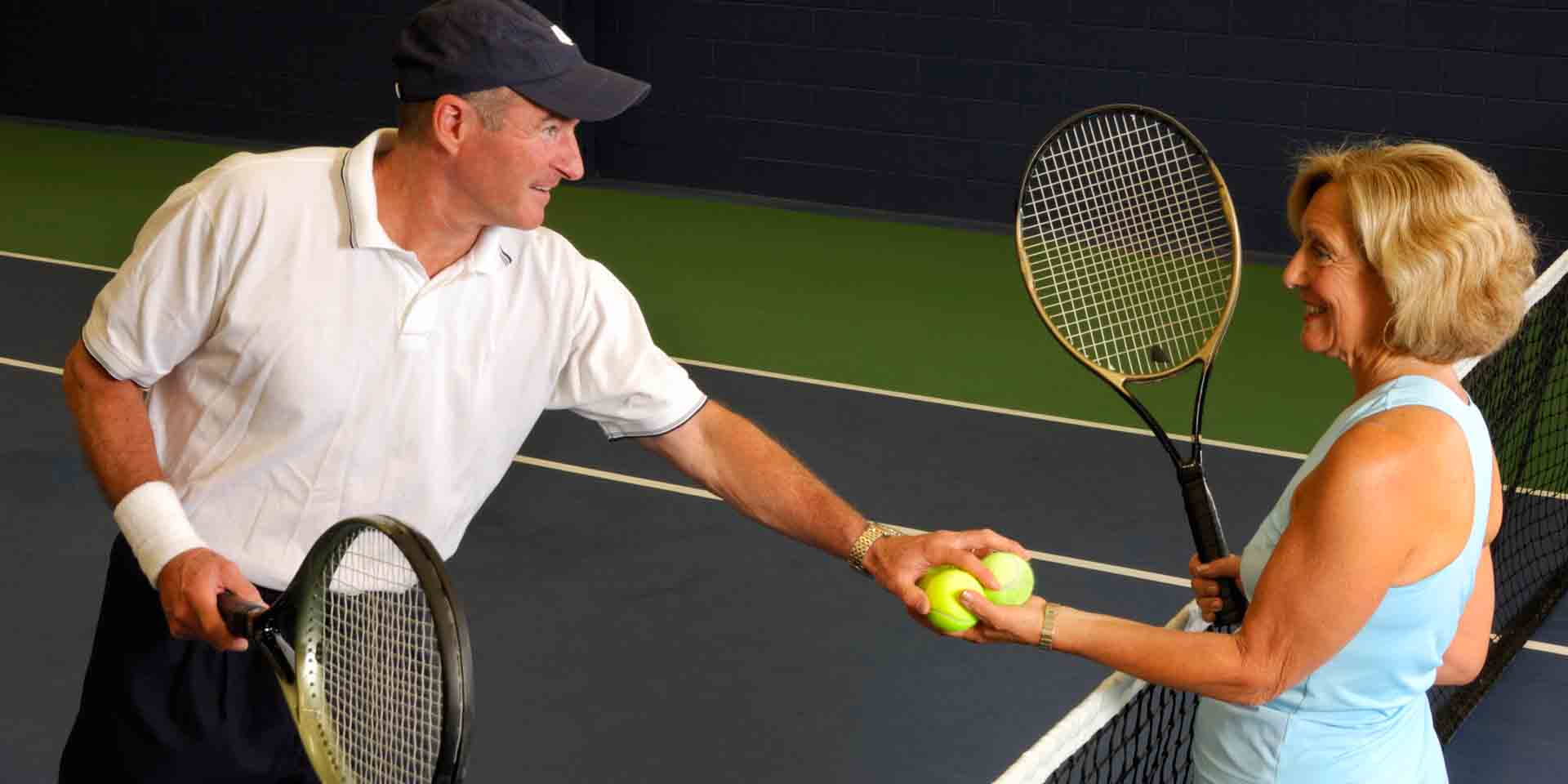 Man and woman holding tennis balls