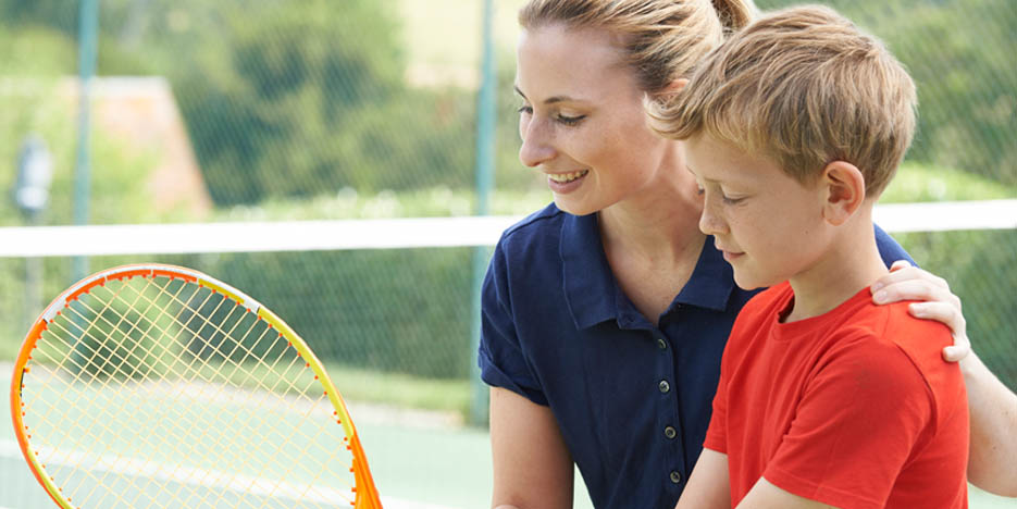 Mom helping son with tennis racket
